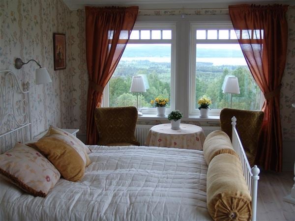 Double room with floral wall paper and red curtains.  