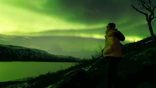 Person ser på nordlys dekt himmel