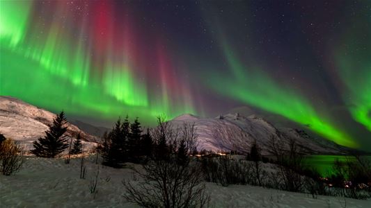 Grønt og rødt nordlys over fjell