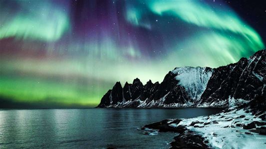 Nordlys over fjell ved kysten