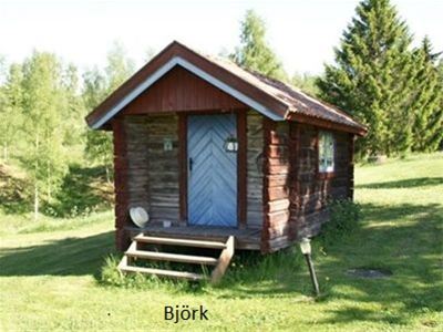 Cabin Björk is a small timber cottage with red linings and a blue door. 