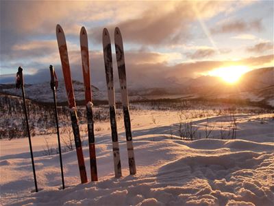 Ski og staver står klar i snøen mens solen skinner