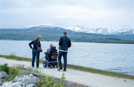 Tre personer på tur med snødekte fjell i bakgrunnen