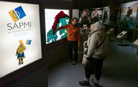 En guide viser to personer norsk kart og samisk historie