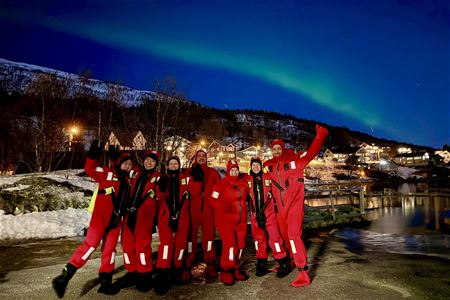Flere gjester som står under nordlyset i tørrdrakter