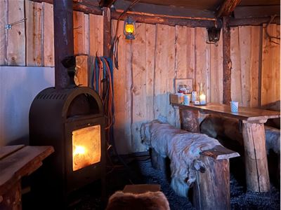 Inne i en koselig hytte med fyr i ovnen