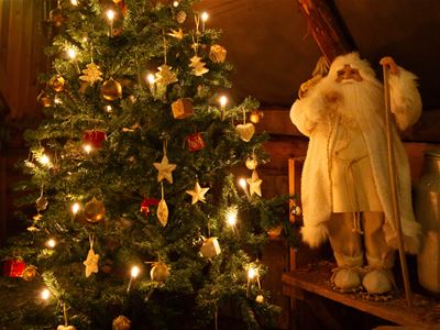 A Christmas tree with a Santa doll beside it