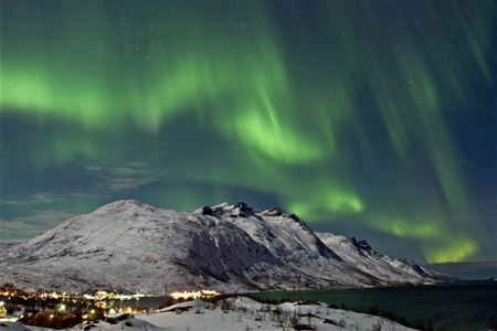 Nordlyset lager bølger over et stort fjell