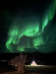 Northern lights over  a field and mountainous landscape