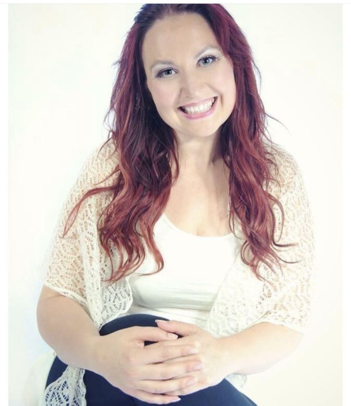 En person med långt rött hår som ler.