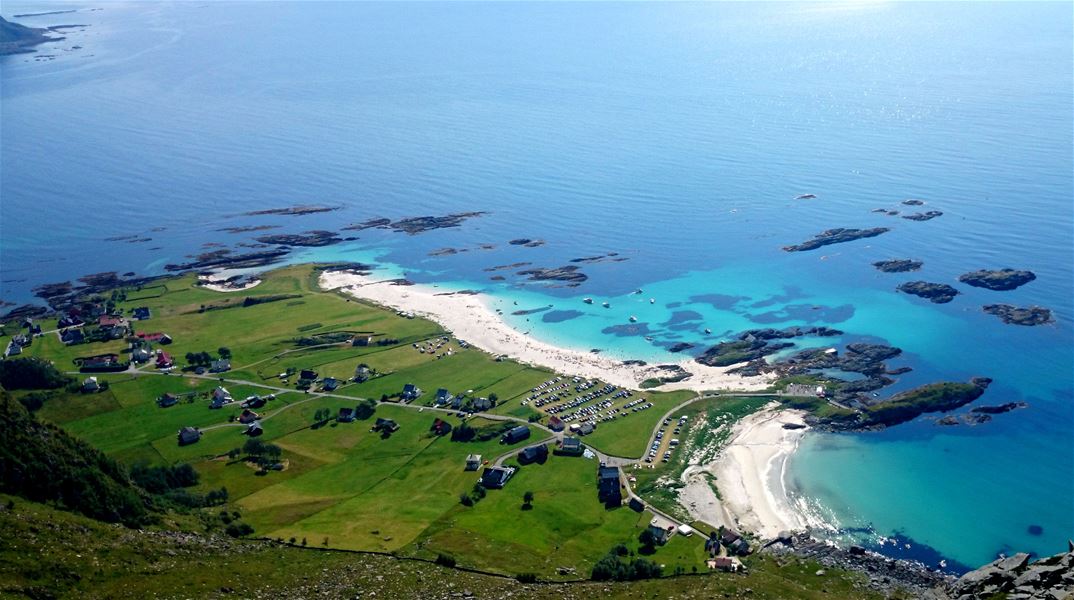 Grotlesanden, Luftfoto av kystlandskap med grønne jorder, hus og veg, kvit sandstrand og turkis sjø med små øyar..