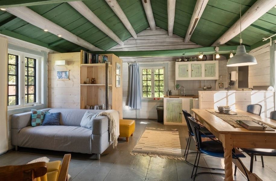 Innendørs bilde av et tømmerrom med trebord og vindu som slipper inn varmt dagslys, omgitt av naturlige trematerialer.