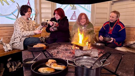 Sámi shaman with guests sitting around a bonfire