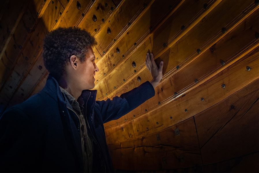 A visitor examining the details of the impressive Viking ship.