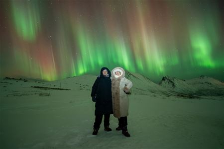 Streams of Aurora dance behind a couple