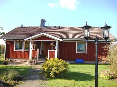 Red single storey villa on a summer day.