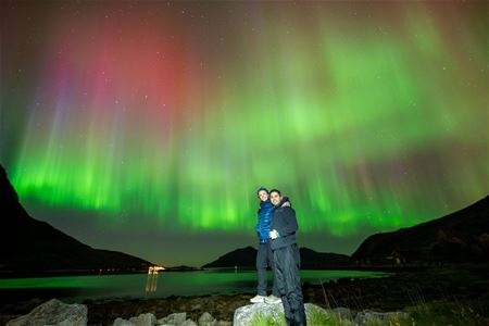 To gjester poserer foran et vidunderlig nordlys-show