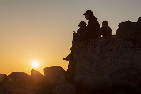 En gruppe som sitter på en stein og ser på midnattssola