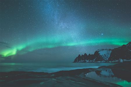 Nordlys med det arktiske landskapet i bakgrunnen