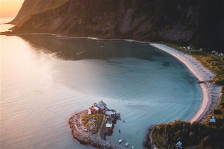En liten øy med et hus, havet og fjell i bakgrunnen