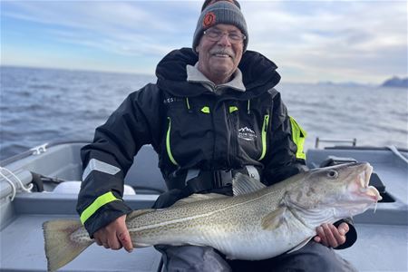 En person som holder en stor fisk på en båt