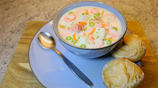 Fiskesuppe med brød ved siden av
