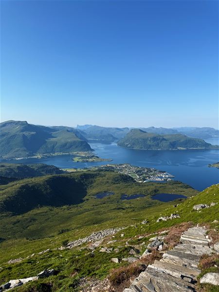 Tarvaldseggja - Topptur Ved Storhavet i Selje –Panorama frå fjellside med steintrapp i framgrunnen, utsyn mot blå fjord, grøne fjell og klar himmel..
