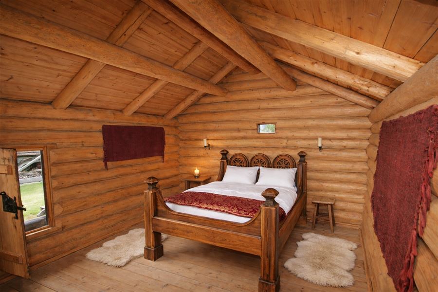 Bedroom in a traditional log building with a double bed and wooden interior.