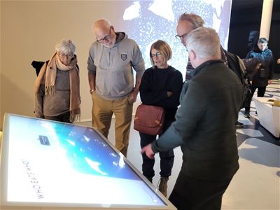 Gjester som følger med på en av skjermene i museumsutstillingen