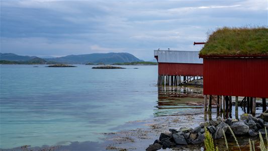 Buildings by the shoreline with mountains in the background