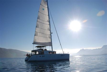 The sailing boat with the sun and mountains in the background