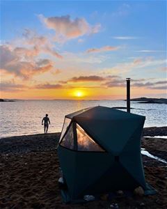 View of the shoreline, the sauna and a person near the sauna
