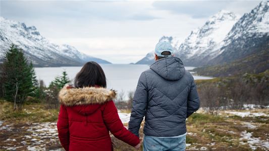 Two guests holding hands while looking out over a fjord