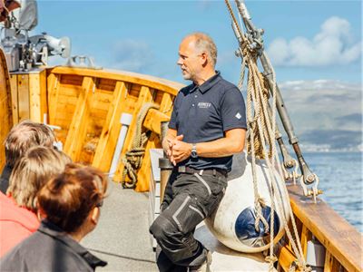 The skipper sharing information with the guests while the boat is sailing