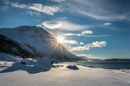 
Sol som kommer frem bak fjell i et vinterlandskap