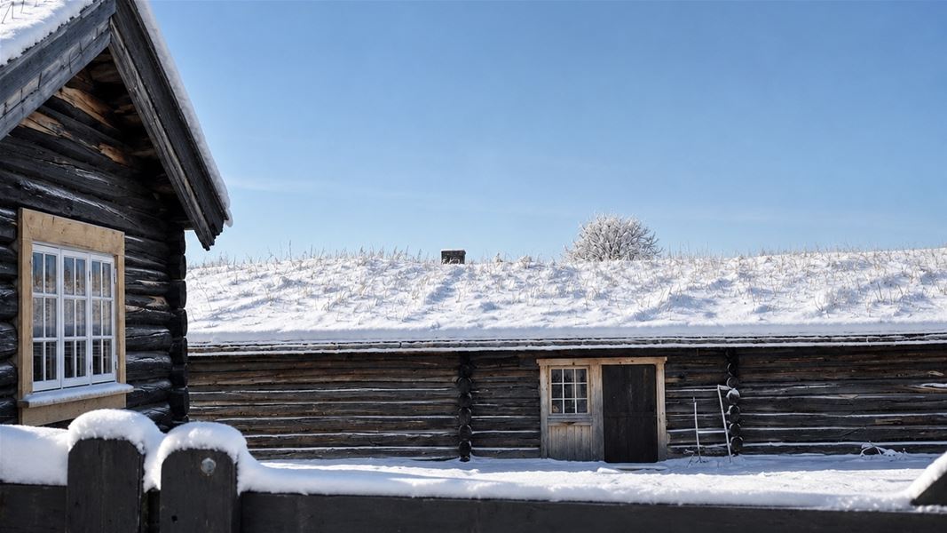 Tradisjonell tømmerhytte omgitt av vinterlandskap.