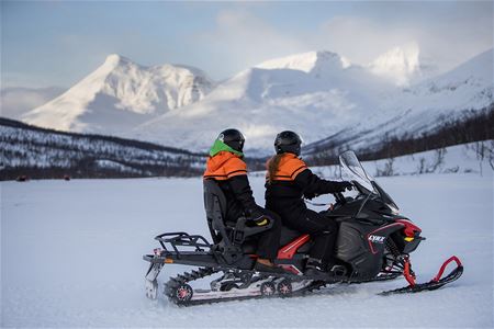 Guests sit on the snowmobile and look out over the mountains