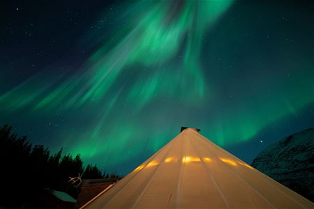 Night photo of the lavvo under a Northern Lights show