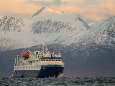 The boat at sea with high mountains in the background