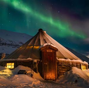 Nordlys over en lavvo i et vinterlandskap