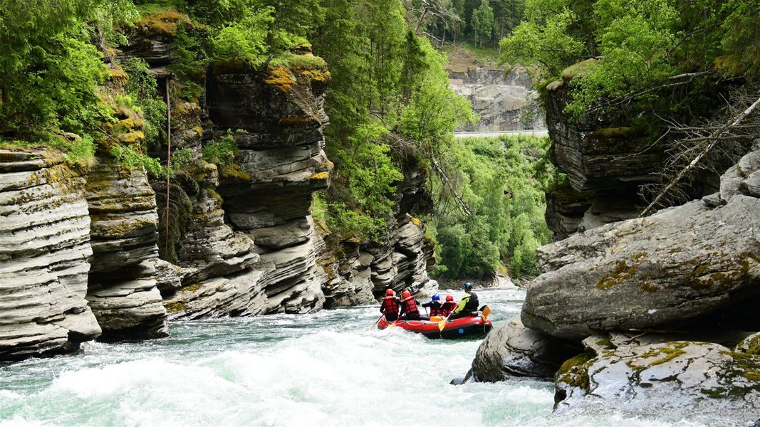 Rafting through a narrow canyon with river and forest.