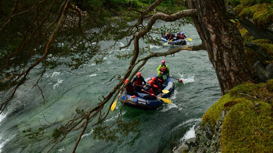 Rafting boat on a river surrounded by trees and rocks.