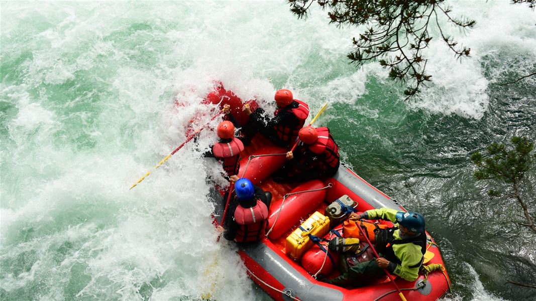 Rafting boat in powerful rapids viewed from above.