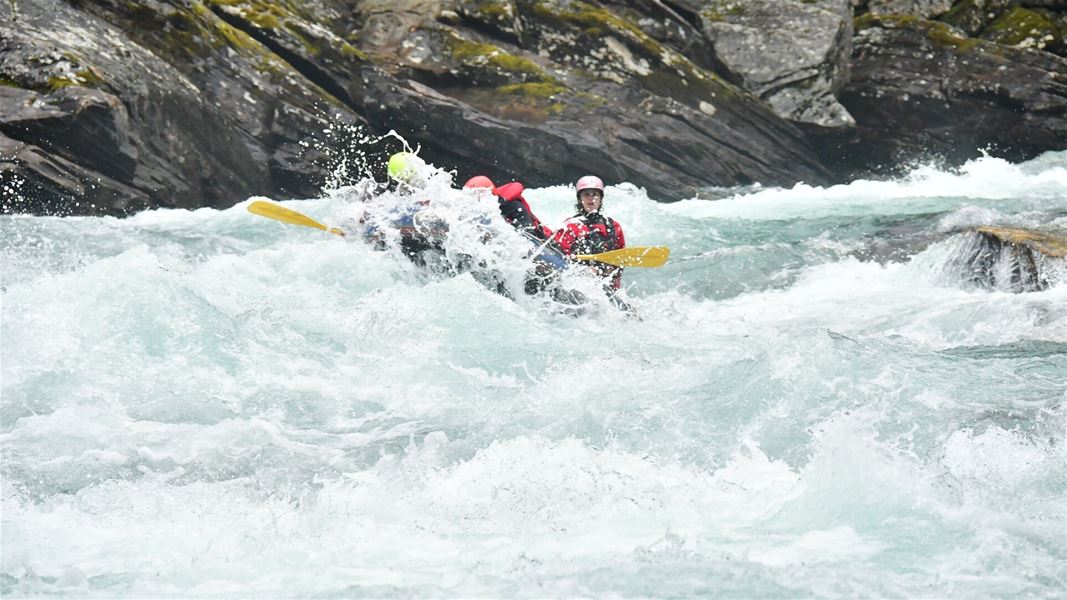Raftingbåt i kraftige stryk mellom fjellvegger.