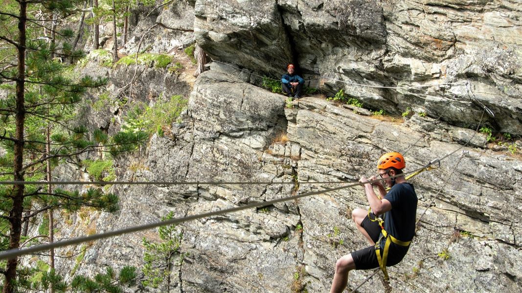 erson traversing a secured rock wall on a via ferrata route.