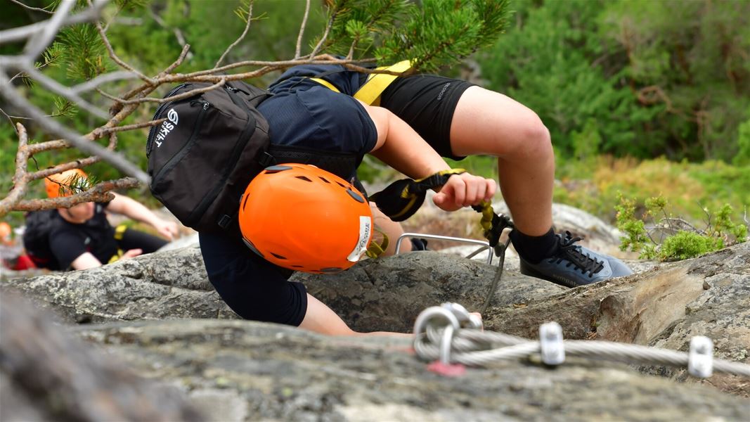 Person wearing a helmet climbing a secured rock face.
