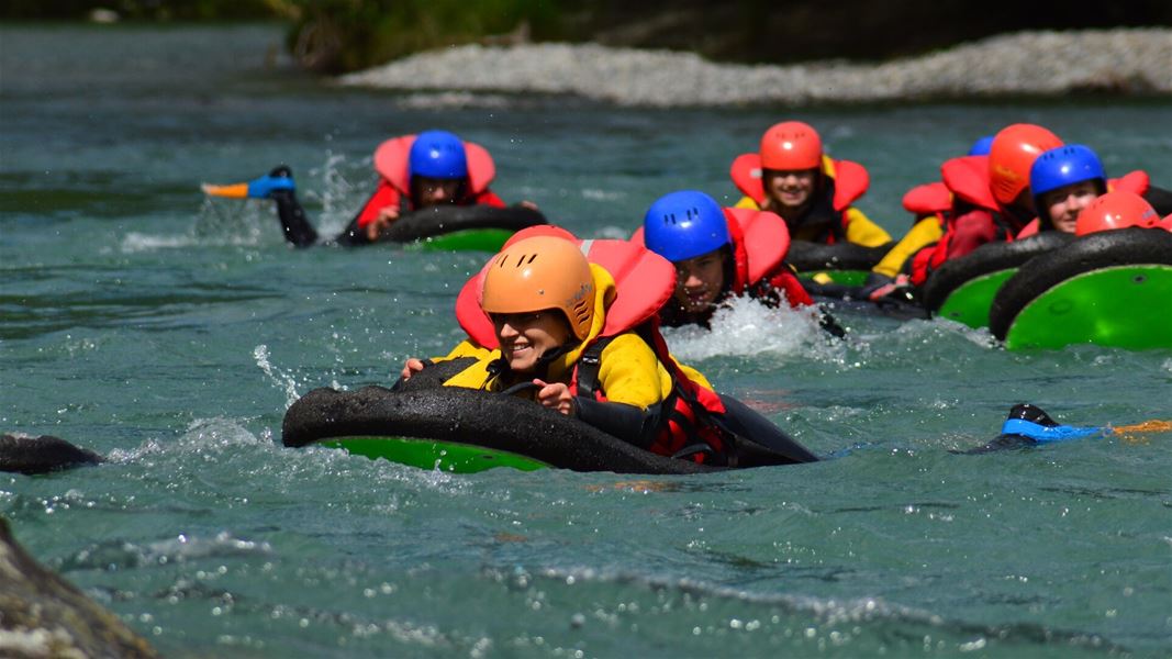 Group wearing helmets and flotation gear in river rapids.