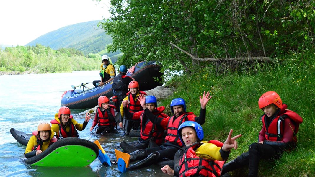 Group gathered by the riverside with rafting equipment