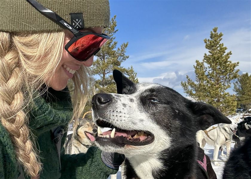 Nærbilde av sledefører og husky i vintervær.