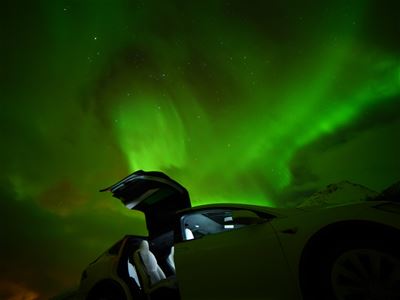An open car door with the northern lights in the background